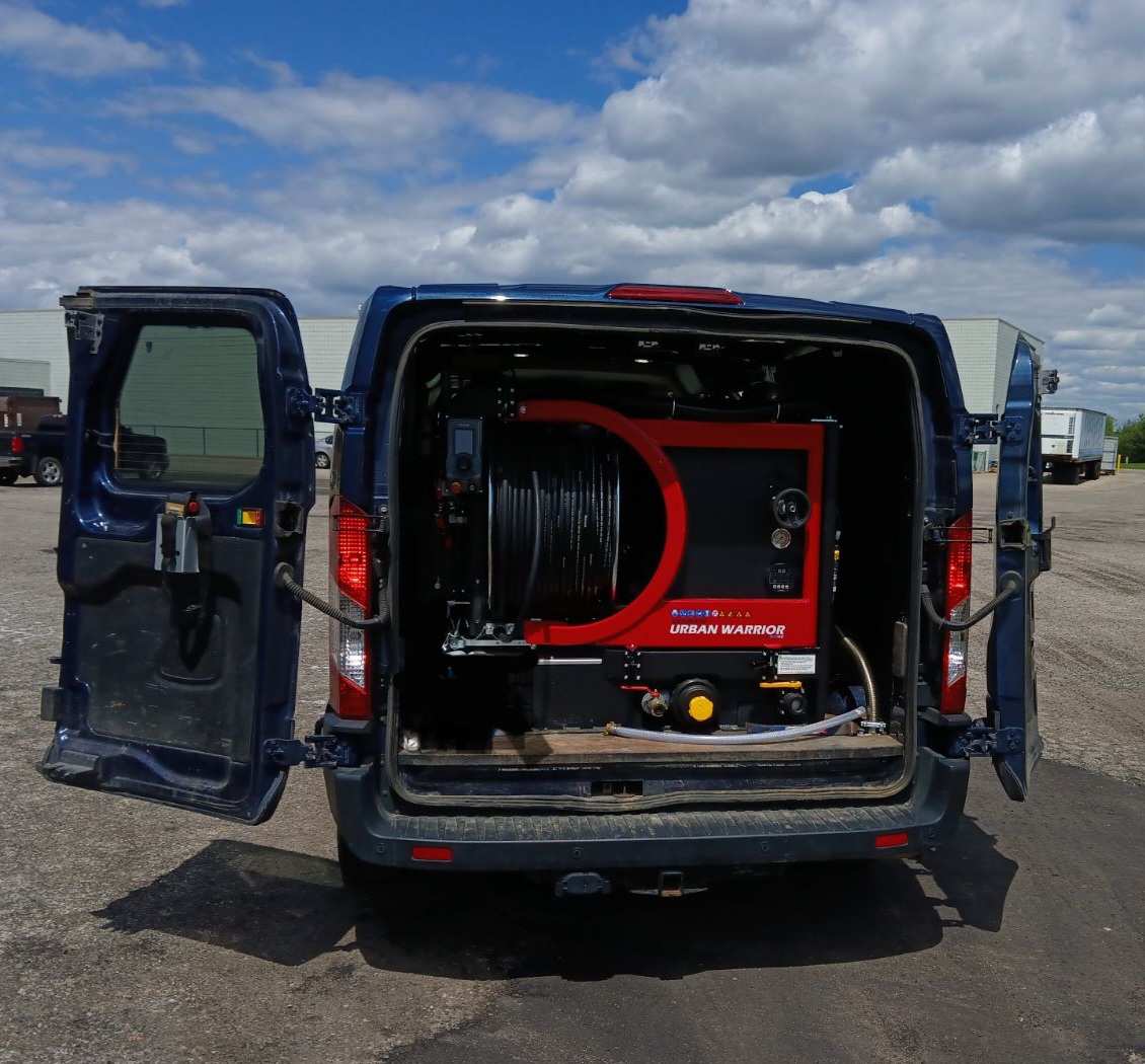 A van with the back door open and a hose attached to it.